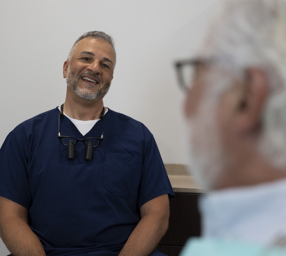 Dentist smiling while talking to a patient in the dental chair