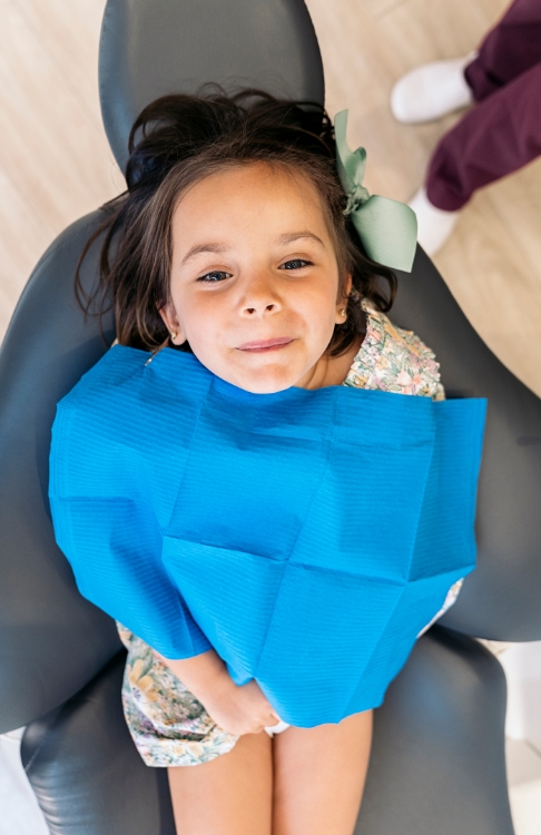 Young girl in dental chair looking up toward the camera