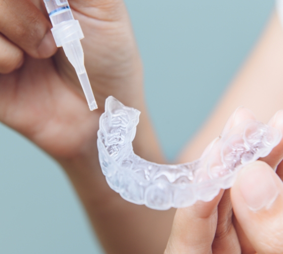 Person placing teeth whitening gel into a dental tray