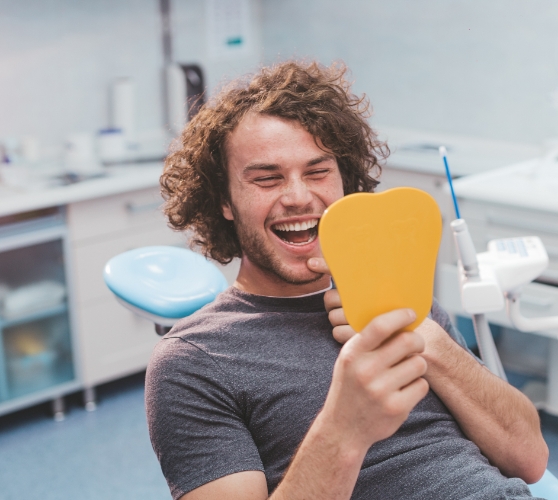 Dental patient looking at his smile in mirror