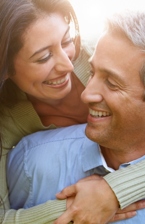 Man and woman smiling at each other with dental implants in Easton