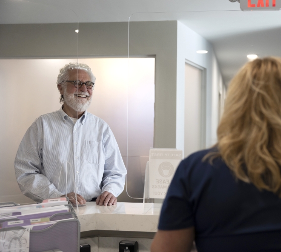 Senior man smiling at receptionist at Easton Dental Specialists