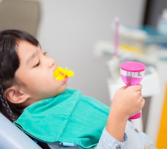 Child in dental chair with fluoride on their teeth