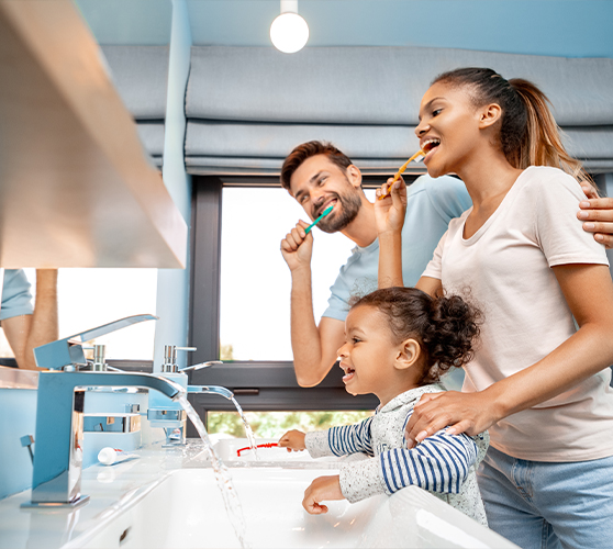 Mother father and young child brushing their teeth together