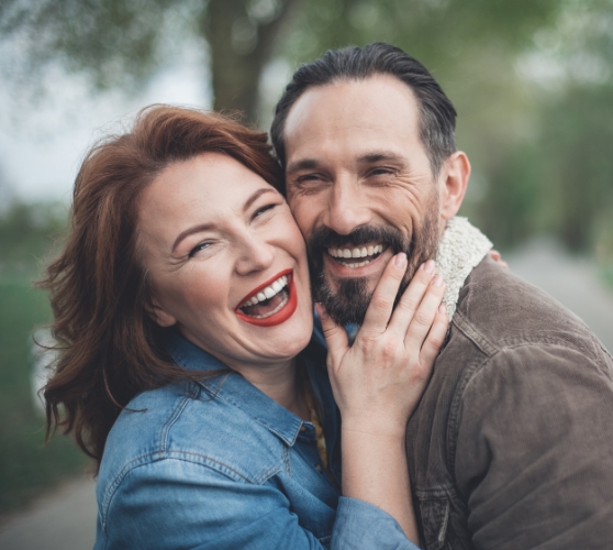 Smiling man and woman hugging outdoors