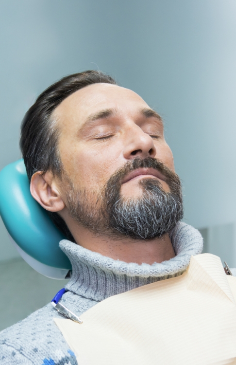 Man relaxing in dental chair thanks to sedation dentistry in Easton