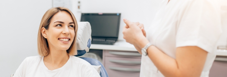 Woman in dental chair listening to her dentist talk