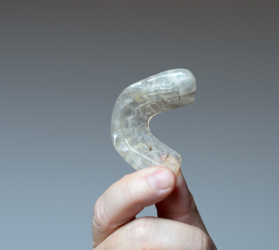 Hand holding a white occlusal splint